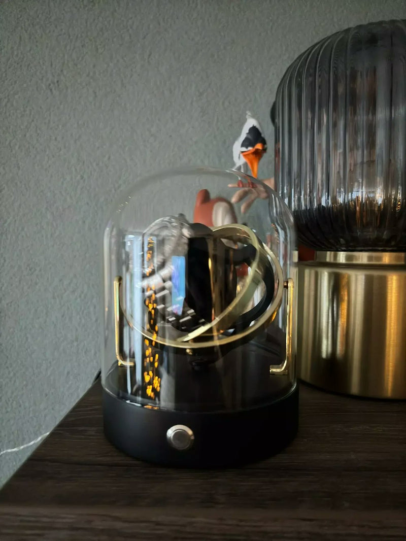 Glass dome watch winder with gold base displaying a watch